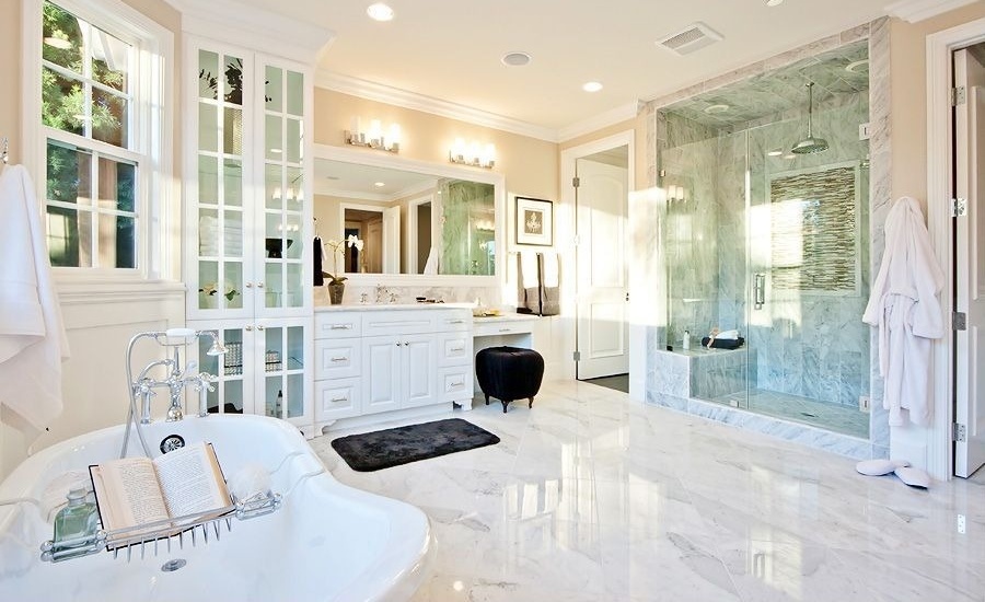 Marble flooring anchors this bright bathroom, featuring full height glass door cabinets next to a