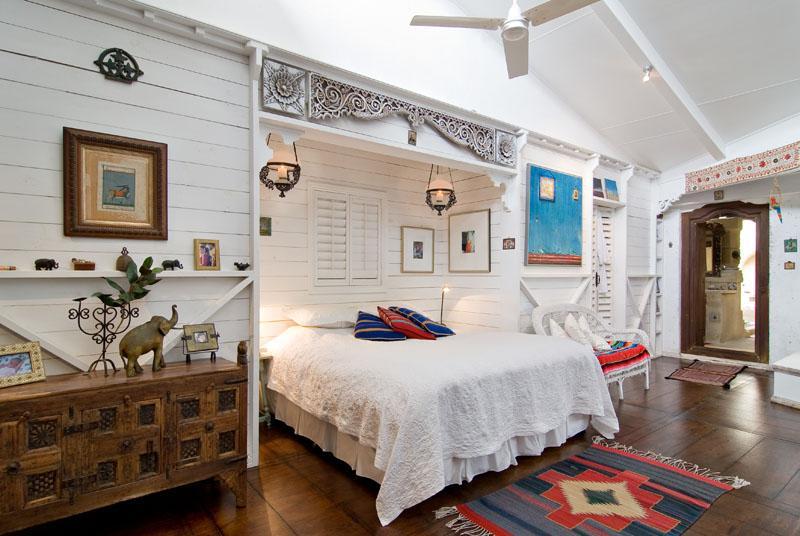 Eclectic bedroom with traditional wooden furniture and dark wood flooring.
