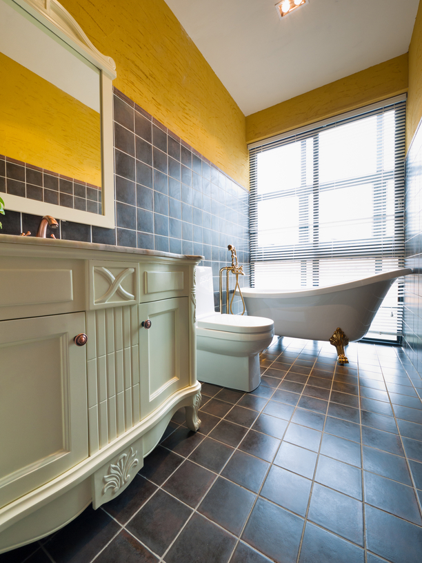 Stylish yellow and dark-tone bathroom with white cabinets