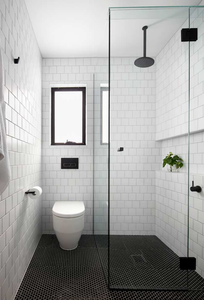 black and white bathroom with rectangular tiles and a ceiling shower to give it a more industrial touch