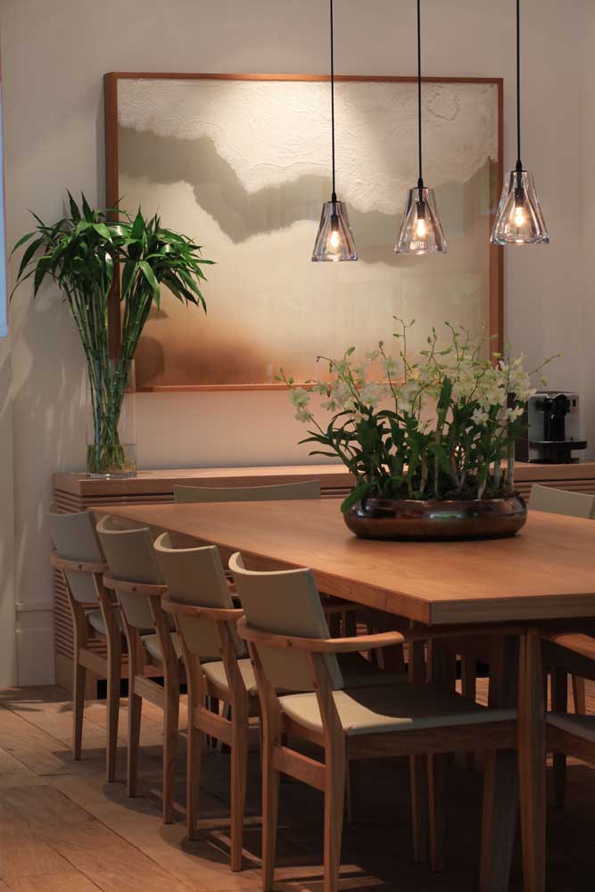 35. The trio of pendant lamps enhances the arrangement of orchids on the dining table.