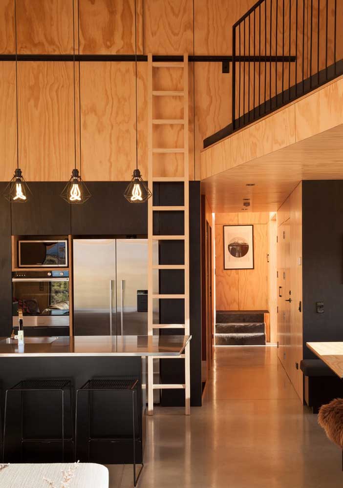 40. Different, this small American kitchen is integrated into the mezzanine by the stairs on the rail; the black furniture harmonizes with the wood used in the cladding of the house.